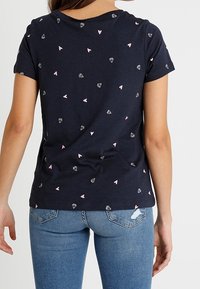 Námornícky bavlněný tričko s krátkým rukávem, zdobené rozptýleným vzorem malých růžových srdíček a diamantových tvarů. Měkká textura a regular fit.