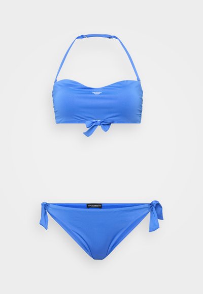 Blå bikinitopp med en bandeau-design och knut framtill samt justerbara axelband, och låga bikinibyxor med sidband. Slät textur.