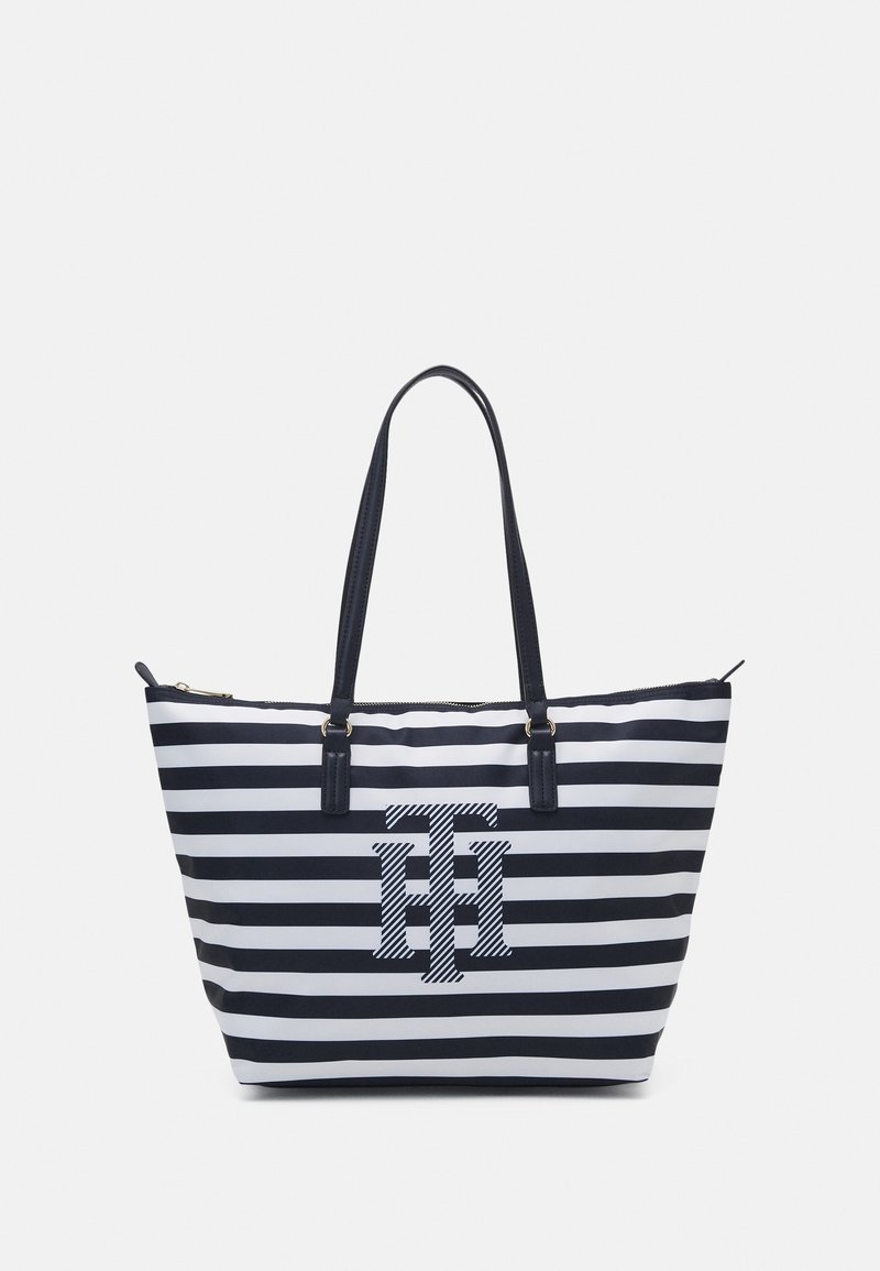 Laulukas navy ja valkoinen raitainen olkalaukku, jossa on kaksinkertaiset kantokahvat, vetoketjukiinnitys ja silmiinpistävä logo keskellä. Valmistettu kestävästä kankaasta.