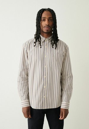 Napapaita, jossa on pystysuorat raidat kermansavun, laivastonsinisen ja tummanruskean väreissä. Varustettu pistenäytöllä ja yhdellä rintataskulla. Puuvillacolla.