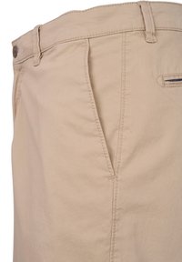 Beige Baumwollhose mit glatter Textur, ausgestattet mit einer Vordertasche, Gürtelschlaufen und einer Gesäßtasche mit sichtbarer Naht und Stickerei.
