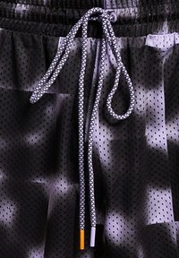 Svarte mesh-shorts med perforert tekstur. Har tykke snorstrammere med et svart-hvitt mønster og detaljer i oransje og grått.