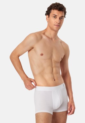 Witte katoenen boxershorts met een aansluitende pasvorm, voorzien van een soepele tailleband en minimale naden, gepresenteerd op een mannelijk model.