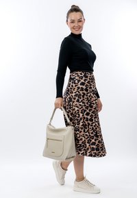 Black ribbed long-sleeve top, beige leopard-print midi skirt, white sneakers, and a textured beige handbag with a front pocket.