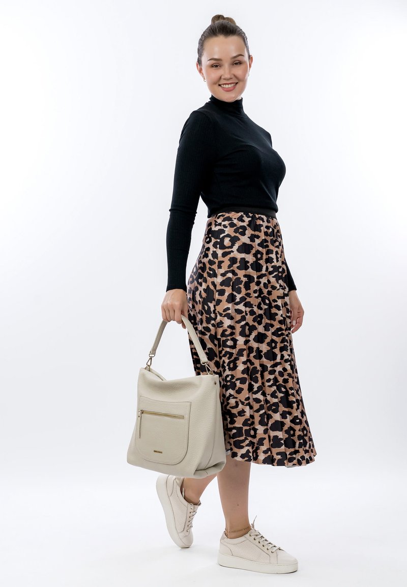 Black ribbed long-sleeve top, beige leopard-print midi skirt, white sneakers, and a textured beige handbag with a front pocket.