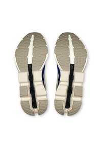 Running shoes featuring a beige rubber outsole, dark blue upper, white accents, textured grip, and a central black cushioning element.
