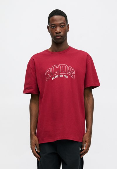 Burgundska pamučna majica s okruglim izrezom i kratkim rukavima, s bijelim natpisom "GCDS MILANO ITALY 1988" otisnutim na prednjoj strani.