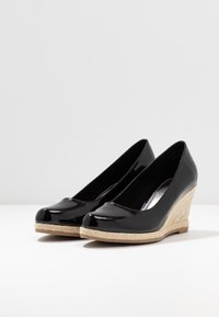 Zapatos de cuña de charol negro con punta redonda, que cuentan con una plantilla de yute trenzado y una suela de goma sólida.