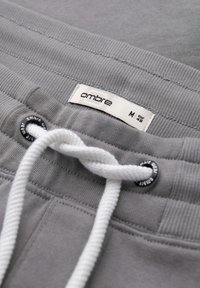 Grå sweatpants med en vit dragsko, med en tyglapp märkt "ombre" och ribbade muddkanter och midjeband.