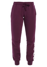 Lilla sweatpants lavet af blød stof, med elastisk talje og snor, sidelommer og et stort hvidt logo på det ene ben.