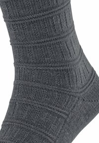 Calzino grigio lavorato a maglia con motivi a coste e texture, caratterizzato da linee orizzontali e verticali. Materiale morbido e forma sagomata.
