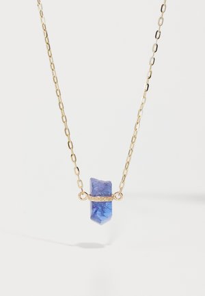 Collier en chaîne dorée avec un pendentif en pierre bleue, présentant une texture lisse, une forme angulaire et des accents décoratifs dorés.