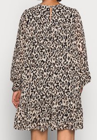 Robe à imprimé léopard avec manches longues, dos froncé, ourlet volanté et fermeture à bouton au cou, présentant une texture de tissu léger.