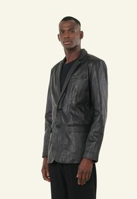 Zwart leren blazer met een gestructureerde afwerking, sluiting met één knop en gesneden revers, voorzien van twee voorzakken en een slim-fit ontwerp.