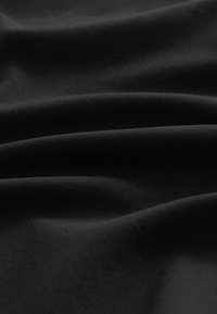 Tissu noir avec une texture lisse et douce, présentant de légers plis qui créent des ombres et des reflets subtils sur la surface.