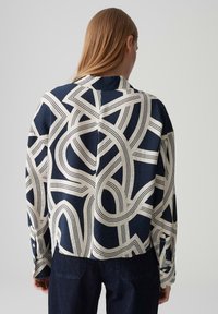 Camicia a maniche lunghe blu navy e crema con un motivo geometrico astratto, tessuto visibile e una vestibilità comoda.