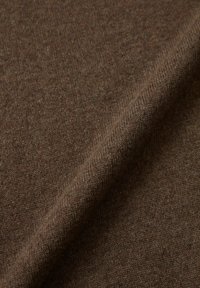 Tessuto marrone con una finitura morbida, che mostra una superficie liscia e un motivo sottile e uniforme. Ideale per abbigliamento o tappezzeria.