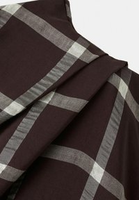 Tissu marron foncé avec un grand motif à carreaux beige et gris, présenté en gros plan avec texture et plis visibles.