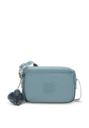 Blue nylon crossbody bag with a zip closure, textured surface, round logo patch, and a monkey keychain accessory for detail.