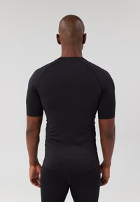 Black short-sleeve athletic shirt, fitted design, smooth texture, and minimalist style; minimal seams at shoulders provide added comfort.
