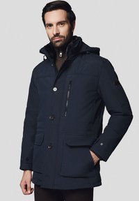 Granatowa pikowana zimowa kurtka z kapturem wyłożonym futrem, z zapięciem na guziki i zamek błyskawiczny oraz wieloma kieszeniami. Charakteryzuje się dopasowanym krojem i miękką teksturą.