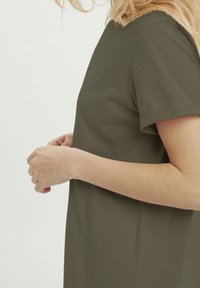 Olivgrünes T-Shirt mit lockerer Passform, kurzen Ärmeln und glatter Textur. Merkmale ein schlichtes Design, runder Ausschnitt und keine sichtbaren Muster.