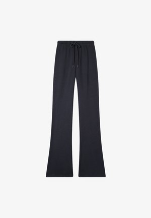 Spodnie dresowe w kształcie dzwonów w ciemnym granacie. Wykonane z miękkiej mieszanki bawełny, z elastycznym pasem w talii oraz sznurkiem do regulacji, bez widocznych wzorów lub elementów metalowych.