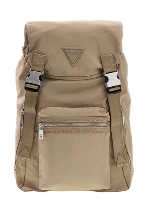 Sac à dos beige avec poche avant zippée, bretelles réglables avec boucles argentées, et patch logo triangulaire Guess sur le rabat supérieur.