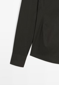 Dark green long-sleeved shirt with a smooth texture, buttoned cuff, and clean lines. The fabric appears lightweight and breathable.