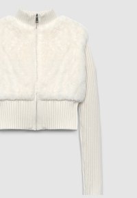 Maglione bianco a maniche lunghe con design a coste, colletto alto e morbida texture in pelliccia sintetica sul davanti. Maniche lunghe a coste.