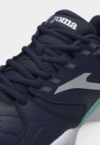 Zapatilla deportiva Joma azul marino con parte superior de malla, cordones azul marino, logo plateado en el lateral y suela blanca con acento en turquesa claro.