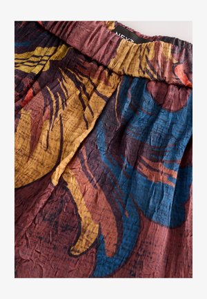 Multicolored skirt featuring a textured fabric with a crinkled design. Bold patterns in shades of blue, yellow, and burgundy with an elastic waistband.