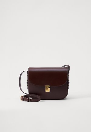 Bruine leren tas met een klepsluiting, gouden accenten en een verstelbare schouderriem. Heeft een gladde textuur en een slanker rechthoekig ontwerp.