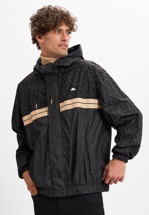 Chaqueta cortavientos negra con capucha, que presenta franjas beige en el pecho y puños y dobladillo elásticos. Tejido con un brillo moderado.