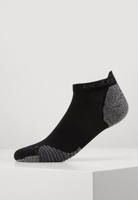 Calcetín negro hasta el tobillo con un talón y punta de color gris texturizado, presentando un cuerpo liso y un logo sutil a lo largo de la banda superior.
