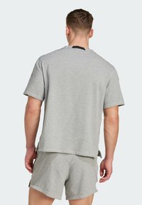 T-shirt gris à manches courtes en mélange de coton doux, présentant un col rond et un ourlet arrière légèrement plus long. Coupe décontractée.