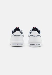 Białe sneakersy z granatowymi akcentami, z materiału sztucznej skóry, z teksturowanym wykończeniem i logo w czerwono-biało-niebieskich kolorach na pięcie.