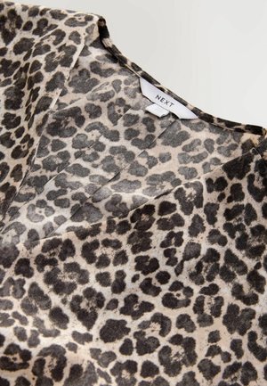 Top con stampa leopardata in beige chiaro e nero, con scollatura a V e texture liscia, dotato di un'etichetta con la scritta "NEXT" vicino alla scollatura.