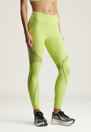 Neon gröna leggings med hög midja, med diagonala svarta ränder och texturerade detaljer vid låret. Stretchigt tyg, atletisk passform.