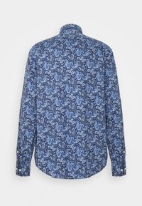 Långärmad skjorta med knappar i blått och vitt paisleymönster, visad bakifrån mot en plain vit bakgrund.