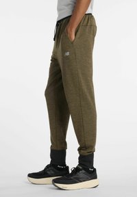 Olivinvihreät lenkkihousut, jotka on valmistettu teksturoidusta kankaasta, varustettu joustavalla vyötärönauhalla, sivutaskuilla ja pienellä heijastavalla logolla reidessä.