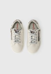 Beige leather sneakers with silver glitter laces, a zipper accent on the side, and a patterned fabric lining. Slim, rounded design.