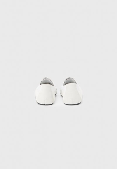 Λευκά παπούτσια slip-on με λείο φινίρισμα, στρογγυλεμένη μύτη και μινιμαλιστικό σχεδιασμό. Διαθέτουν γκρι εσωτερικό και μαύρη σόλα.