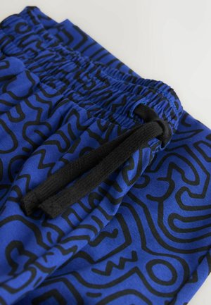 Blaue Shorts mit einem schwarzen abstrakten Muster, elastischem Bund mit Kordelzug und glatter Stofftextur.