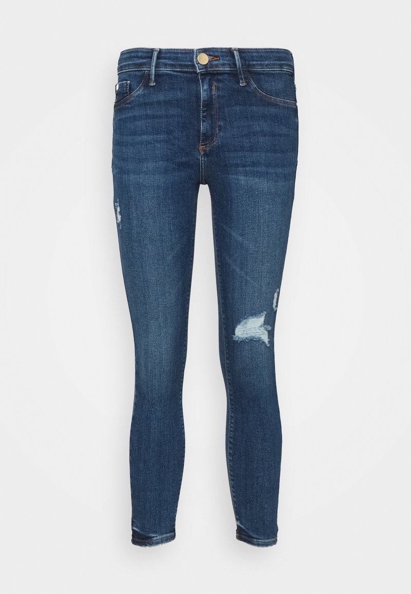 Dark blue skinny jeans made of denim, featuring a mid-rise waist, slight whiskering, and distressed areas on the thighs.