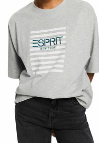 Grå oversized t-shirt med rund halsringning, med ett randigt mönster och "ESPRIT NEW YORK" logotyp i teal och svart broderi.