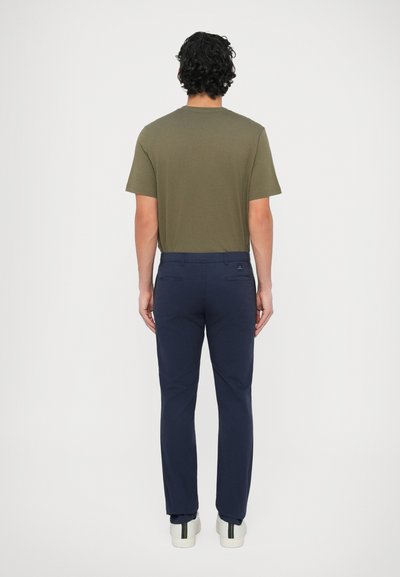 Krátke tričko olivovo zelenej farby s krátkym rukávom v kombinácii s tmavomodrými nohavicami. Tričko má okrúhly výstrih, nohavice sú úzkeho strihu a majú zadné vrecká.