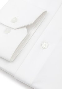 Biała koszula z klasycznym kołnierzykiem, z perłowymi guzikami i gładką fakturą materiału. Widoczne złożony kołnierzyk i mankiety.