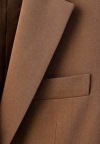 Chaqueta de traje marrón con una tela texturizada y tejida. Presenta un solapa y un único bolsillo en el pecho con un acabado limpio.