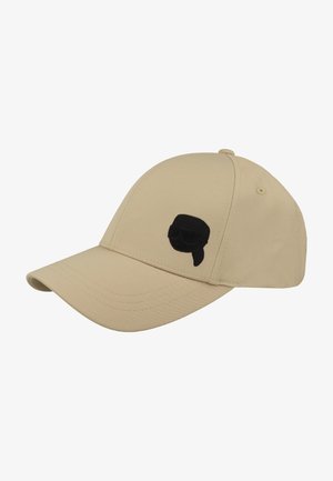 Gorra de béisbol beige con visera curva y una pequeña cara negra bordada que lleva gafas de sol y un pañuelo en el panel frontal.